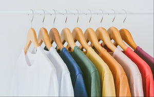 Several t-shirts of different colors hanging on hangers
